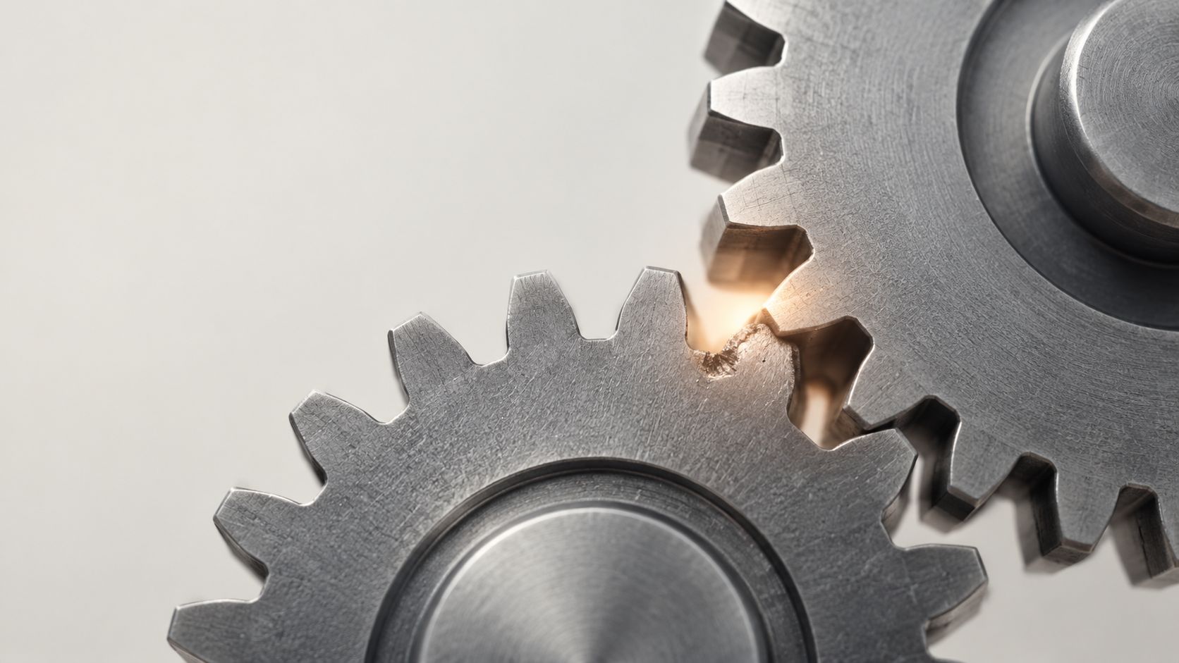 Close-up of two interlocking metal gears showing a damaged tooth at the point of contact