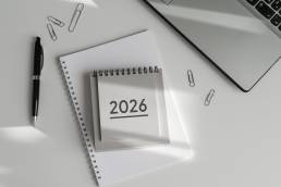 a Top-down view of desk with 2026 calendar, notebooks, pen and paperclips. Ideal for themes of business, organization, and professional planning