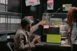 Two inspectors using greenscreen on laptop at desk